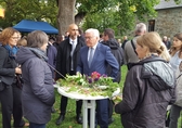 Frank-Walter Steinmeier steht mit Mitarbeitenden der hessischen Landeskirchen an einem geschmückten Stehtisch und unterhält sich. Im Hintergrund zu sehen: ein großer noch voll belaubter Baum und Kirchenmauern